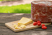 Delicious Italian Pecorino toscano cheese with cherry tomatoes served on cutting board on wooden table in garden