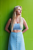 Millennial junge blonde Frau mit blondem Haar schaut weg auf grünem Hintergrund