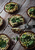From above of cauliflower and walnut cakes with greens near fork on planked wooden table