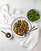 Draufsicht auf köstlichen Salat mit Rucola und Quitten, serviert auf einem Teller mit Soße auf dem Tisch