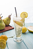 Von oben kalter Birnencocktail im Glas mit Rosmarin und Eiswürfeln auf einem Tisch mit frischen Früchten