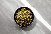 Top view of bowl full of tasty canned peas and placed on gray table in kitchen
