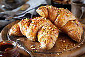 Leckere vegane Croissants mit zerstoßenen Haselnüssen zum Frühstück auf einem dunklen, rustikalen Holzschneidebrett