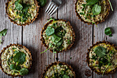 Top view of cauliflower and walnut cakes with greens near fork on planked wooden table