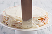 Metallspachtel auf Keto-Krepp-Torte mit Erythrit-Süßstoff und Glasur aus Frischkäse und Schlagsahne, die auf dem Tisch serviert wird