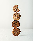 Delicious sweet cookies with chocolate chips stacked on top of each other on table against white background in light kitchen