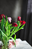 Glasvase mit roten Tulpen auf dem Tisch am Fenster