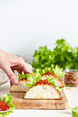 Small delicious tacos with red caviar and green lettuce served on wooden cutting board on table