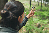 Back view of unrecognizable female looking at wild edible Boletus mushroom with blue cap in woods