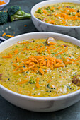 Schalen mit leckerer Suppe mit Brokkoli und Käse auf grauem Tisch in einem Restaurant