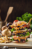 Appetitliche Hamburger mit Gemüse auf Holzbrett mit Pommes frites in Küche