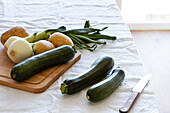 Hoher Blickwinkel auf verschiedene frische Zutaten, die für die Zubereitung einer appetitlichen Zucchinicremesuppe zu Hause vorbereitet werden