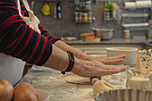 From above of crop unrecognizable elderly cook rolling out crust on table with flour while cooking in kitchen at home