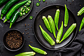 Draufsicht auf reifes grünes Superfood auf schwarzem Keramikteller neben Pfeffer in Schale auf Tisch
