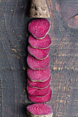 Overhead-Komposition von in Scheiben geschnittener und auf einer schäbigen Holzfläche angeordneter organischer, natürlicher Roter Bete