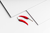 High angle composition of hot red chili peppers arranged plate against white board surface background