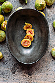 Green fig slices in modern black bowl on the table with grunge texture. minimal concept food. Also known as ripe white figs