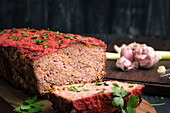 Delicious homemade meat loaf with carrot served with fresh green parsley on wooden chopping board on table