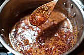 From above of crop anonymous person stirring fig confiture in cooker on stove at home
