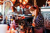 Fokussierte Barkeeperin garniert frische Cocktails in Gläsern, die auf dem Tresen einer Bar stehen
