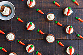 Nahtloses Muster von zusammengesetzten dekorativen süßen Karotten und Muffins mit Sahne auf hölzernem Hintergrund