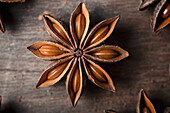 Closeup of aromatic dried anise stars with seeds scattered on rustic wooden table for gastronomy concept background