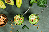 Blick von oben auf Gläser mit gesundem grünen Smoothie aus Avocado, Spinat und Minzblättern