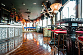 Cozy interior of spacious bar with wooden counter and tables illumined by glowing chandeliers