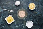Draufsicht auf verschiedene Zutaten für süße Käsewaffeln mit Mehl und geriebener Butter auf einem Tisch mit geriebenem Käse in der Küche
