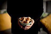 Closeup hands of anonymous woman holding small bowl full of crispy fortune cookies