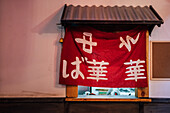 Red cloth with Asian hieroglyphs in window with metal roof of modern building