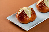 From above fresh salty pretzel buns placed on plate on brown background