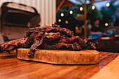 Leckeres gegrilltes Schweinefleisch mit knuspriger Kruste, serviert auf einem hölzernen Schneidebrett auf einem Tisch in einem hellen Café mit professioneller Ausstattung