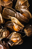 Top view of seamless background of orange physalis placed in rows on black table