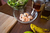 Von oben: Frische Shrimps in einer Glasschüssel neben Kochzutaten auf einem Küchentisch