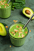 Gläser mit gesundem grünen Smoothie aus Avocado, Spinat und Minzblättern