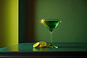 Seitenansicht eines grünen Cocktailglases auf einem Tisch in einem luxuriösen grünen Interieur. Generative KI
