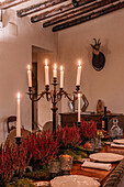 Interieur eines Esszimmers mit Holztisch, Besteck und mit Blumen dekorierten Tellern für das Abendessen