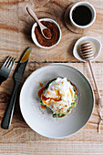 Appetitliche Scheibe Körnerbrot mit Avocado und pochiertem Ei auf einem Teller auf einem Holztisch