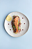 Köstlicher Rotbarbenfisch und verschiedene Reissorten, serviert auf einem Teller mit einer Zitronenscheibe auf einem Tisch im Restaurant