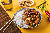 Von oben Kompositionsschüssel mit Kung-Pao-Hühnchen mit weißem Reis, Erdnuss, roter Chilischote, grünen Zwiebeln und Stäbchen