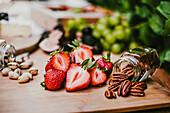 Ripe delicious strawberries in front of figs and grapes on lumber board on table