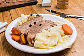 Tasty appetizing slices of spiced corned beef with cabbage and carrot served on plate placed on wooden table