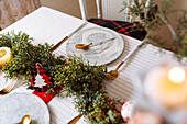 From above christmas table settings with a wreath decoration, red and white, with golden cutlery and candles
