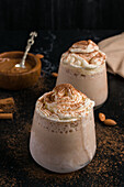 Milkshake with ice vanilla and whipped cream covered with aromatic ground cinnamon in glass