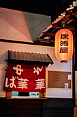 Rotes Tuch mit asiatischen Hieroglyphen im Fenster mit Metalldach eines modernen Gebäudes