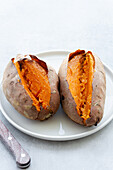 From above appetizing freshly baked sweet potatoes placed on white ceramic saucer on table