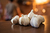 Closeup of fresh garlic heads placed on wooden counter in kitchen for preparing food