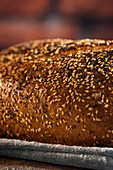 Nahaufnahme von leckerem geschnittenem Brot mit brauner Kruste und knusprigen Sonnenblumenkernen in einem Weidenkorb