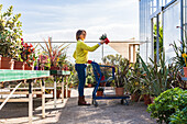 Side view of female customer and with assorted plants in shopping trolley standing in modern garden center